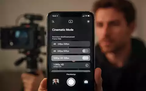 An iPhone screen displaying Cinematic Mode settings, with options for resolution and frame rate, over a blurred background of filming. - Foto: über boerse-global.de
