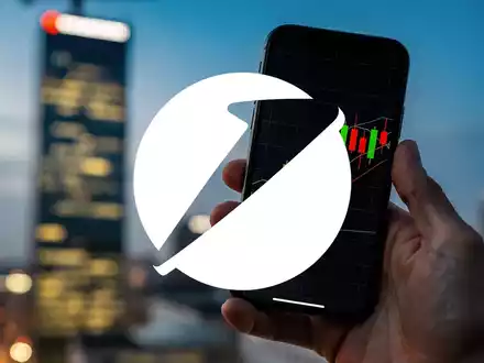 Eine Hand hält ein Smartphone mit Börsenkursen, im Hintergrund verschwommen der Commerzbank-Turm. - Foto: über boerse-global.de
