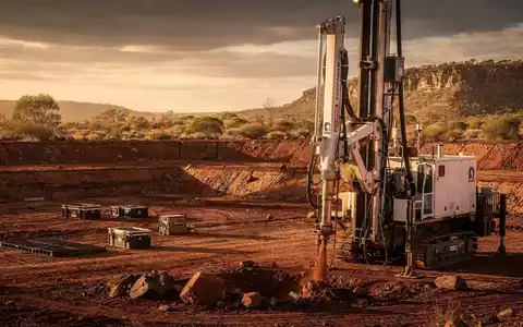 Eine professionelle Fotografie einer australischen Bergbaulandschaft mit einem Bohrer und weitem Outback unter dramatischem Himmel. - Foto: über boerse-global.de