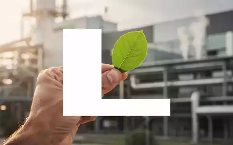 Eine Hand hält ein grünes Blatt vor einem unscharfen Fabrikhintergrund, symbolisiert Nachhaltigkeit und Wachstum für Lenzing. - Foto: über boerse-global.de