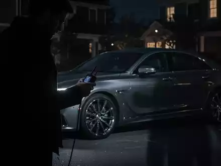 Eine schattenhafte Figur mit einem Signalrelaisgerät steht nachts neben einem Luxusauto. Die Szene betont die Anfälligkeit von Keyless-Go-Systemen. - Foto: über boerse-global.de