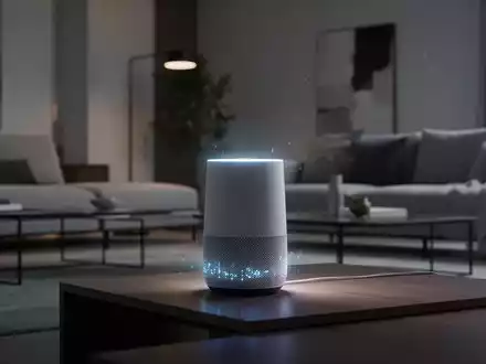 A modern smart speaker device with a subtle glowing light, set in a clean, contemporary living room environment. - Foto: über boerse-global.de
