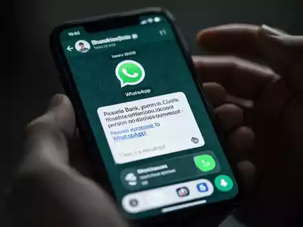 Nahaufnahme eines Smartphones mit einer betrügerischen WhatsApp-Nachricht, die auf Finanzbetrug hinweist. - Foto: über boerse-global.de