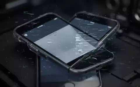 An older model iPhone with a subtle digital glitch effect on its screen, set against a dark, blurred background. - Foto: über boerse-global.de