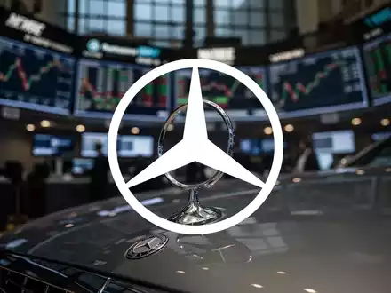 Mercedes-Benz Stern auf Motorhaube, unscharfer Hintergrund mit Börsenparkett bei Dämmerung, der einen Marktabschwung andeutet. - Foto: über boerse-global.de
