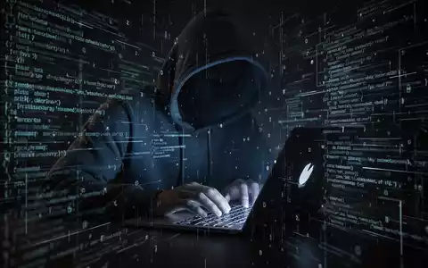 A person in a hoodie typing on a laptop with digital code and data streams, symbolizing a cyber threat and data theft. - Foto: über boerse-global.de