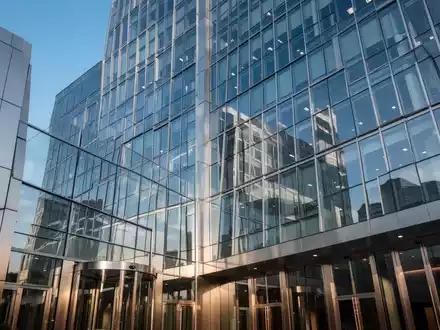 Moderne Glas- und Stahlfassade eines Bankgebäudes, das einen klaren blauen Himmel widerspiegelt. - Foto: über boerse-global.de