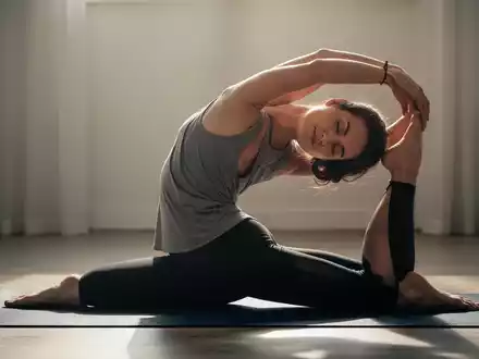 Eine Person dehnt ihren Rücken sanft auf einer Yogamatte in einem ruhigen Raum, was Flexibilität und Entspannung symbolisiert. - Foto: über boerse-global.de