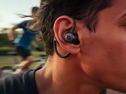 Close-up of a dark Beats Fit Pro earbud in a person's ear during exercise, highlighting its secure wingtip design. - Foto: über boerse-global.de