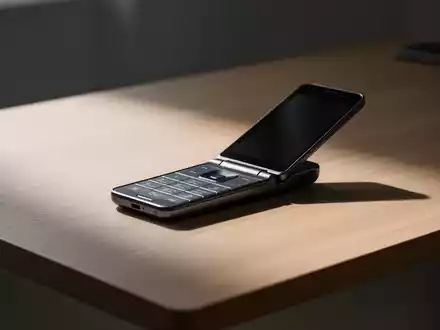 Ein minimalistisches Bild, das ein einzelnes, modernes Klapptelefon auf einem sauberen, aufgeräumten Holzschreibtisch zeigt. - Foto: über boerse-global.de