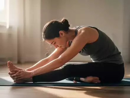Eine Person macht eine sanfte Dehnübung in einer ruhigen Umgebung, die Entspannung und psychische Gesundheit symbolisiert. - Foto: über boerse-global.de