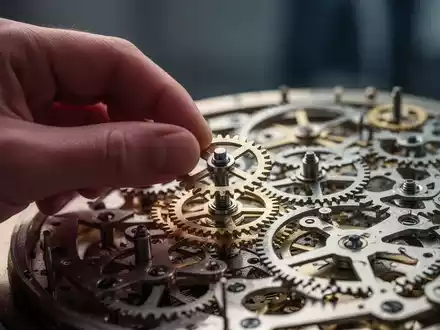 Eine Hand setzt präzise ein kleines Zahnrad in ein komplexes Uhrwerk ein, das finanzielle Reformen und das Gleichgewicht im Gesundheitswesen symbolisiert. - Foto: über boerse-global.de