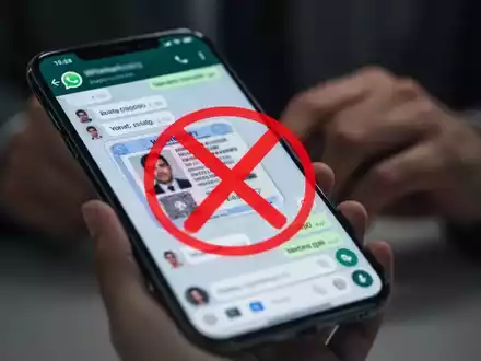 Ein Smartphone zeigt einen WhatsApp-Chat mit einer unscharfen Ausweiskopie und einem roten Warnsymbol, im Hintergrund Hände. - Foto: über boerse-global.de