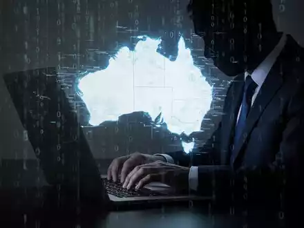 A shadowy figure typing on a laptop with a distorted map of Australia and binary code, representing a cyberattack. - Foto: über boerse-global.de