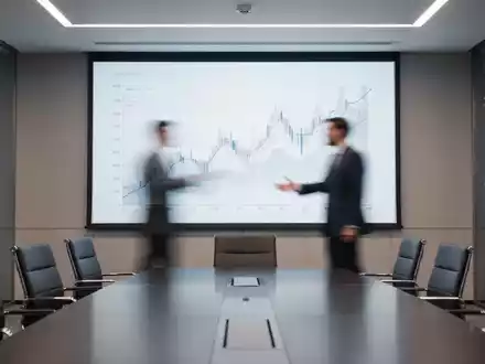 Eine moderne Konferenzszene mit einem Bildschirm, der ein abstraktes Finanzdiagramm anzeigt, und einer Person, die darauf zeigt. - Foto: über boerse-global.de