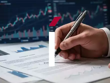 Eine Hand unterschreibt ein Dokument mit einem Stift, mit unscharfen Finanzdiagrammen im Hintergrund. - Foto: über boerse-global.de
