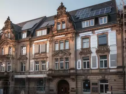 Historische deutsche Wohnhausfassade mit sichtbaren Sanierungsarbeiten und modernen Energieeffizienz-Elementen. - Foto: über boerse-global.de