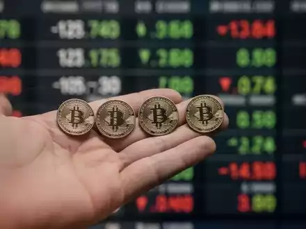 Eine Hand hält fünf identische Finanzmarken, wobei eine leicht getrennt ist, vor einem verschwommenen Börsenticker. Das Bild symbolisiert einen Aktiensplit. - Foto: über boerse-global.de