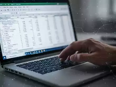A hand types on a laptop keyboard, with a blurred Excel spreadsheet showing data and formulas on the screen. - Foto: über boerse-global.de