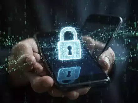 Eine Nahaufnahme einer Hand, die ein Smartphone hält, mit einem digitalen Schloss-Symbol und Binärcode auf dem Bildschirm. - Foto: über boerse-global.de