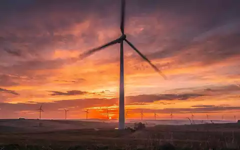Eine Windkraftanlage bei Sonnenuntergang in einer weiten Landschaft, die erneuerbare Energie und Wachstum symbolisiert. - Foto: über boerse-global.de