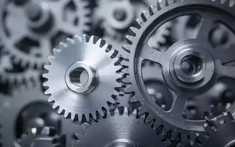 Nahaufnahme von zwei ineinandergreifenden Zahnrädern aus Metall, die Präzision und industrielle Mechanik symbolisieren. - Foto: über boerse-global.de