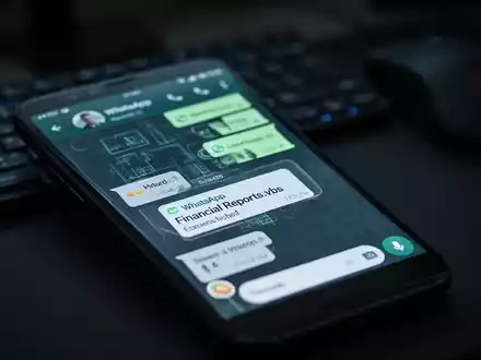 Nahaufnahme eines Smartphone-Bildschirms mit einem WhatsApp-Chat und einer verdächtigen Datei namens 'Financial Reports.vbs'. - Foto: über boerse-global.de