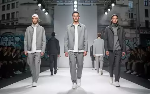 Models präsentieren minimalistische Streetwear auf einem Laufsteg in Berlin, mit urbaner Architektur im Hintergrund. - Foto: über boerse-global.de