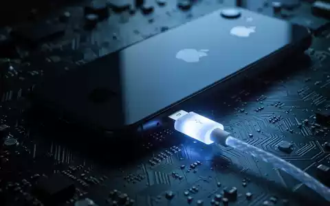 A close-up of an Apple iPhone connected to a circuit board by a glowing USB cable, symbolizing a hardware exploit. - Foto: über boerse-global.de