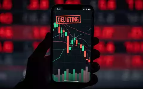 Eine Hand hält ein Smartphone mit einem fallenden Kryptowährungschart und einem 'DELISTING'-Stempel. Im Hintergrund eine unscharfe rote Anzeigetafel. - Foto: über boerse-global.de