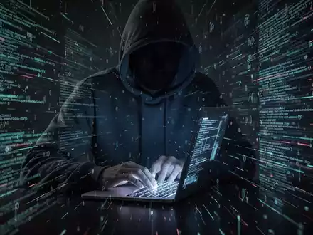 A person in a hoodie typing on a laptop, surrounded by digital code, symbolizing a cyberattack and data breach. - Foto: über boerse-global.de