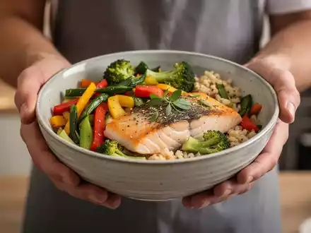 Hände halten eine Schale mit einer gesunden Mahlzeit, die Lachs und frisches Gemüse enthält, als Symbol für eine entzündungshemmende Ernährung. - Foto: über boerse-global.de