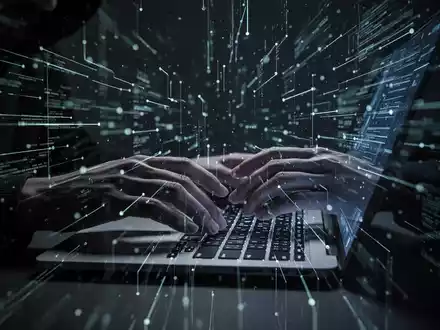 Hände tippen auf einer beleuchteten Laptop-Tastatur, umgeben von digitalen Linien, die Cyberkriminalität und Datenklau darstellen. - Foto: über boerse-global.de