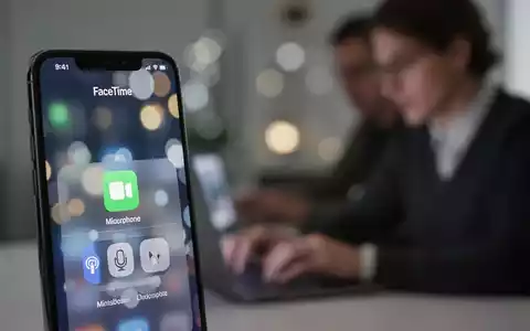 iPhone screen showing FaceTime call and microphone settings, with a blurred background of a person on a laptop. - Foto: über boerse-global.de