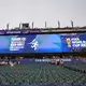 Über die Anzeigentafel werden die Besucher aufgefordert, das Stadion zu verlassen.  - Bild: Petr David Josek/AP/dpa