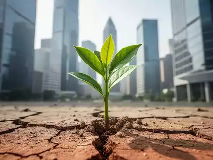 Ein grüner Pflanzenspross bricht durch trockene Erde, im Hintergrund verschwommen Hochhäuser einer Finanzmetropole. - Foto: über boerse-global.de
