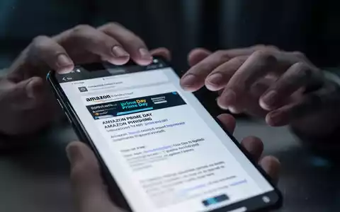 Nahaufnahme eines Smartphone-Bildschirms, der eine gefälschte Amazon Prime Day Phishing-E-Mail anzeigt, mit unscharfen Händen im Hintergrund. - Foto: über boerse-global.de