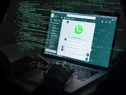 A shadowy figure typing on a laptop with a WhatsApp interface and digital code, symbolizing a malware attack. - Foto: über boerse-global.de