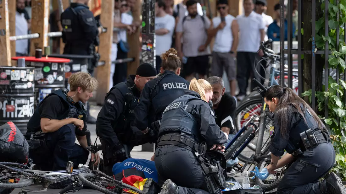 Polizisten knien in der Nähe des Frankfurter Hauptbahnhofs am Boden und kümmern sich um einen Verletzten.  - Bild: Boris Roessler/dpa