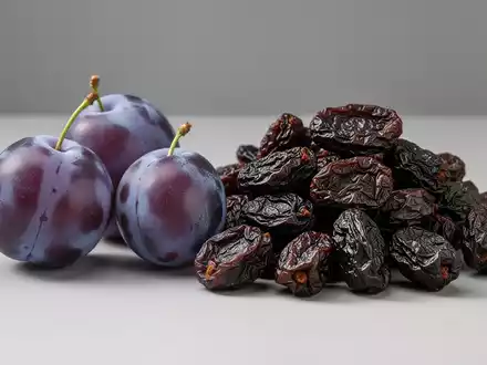 Frische lila Pflaumen und getrocknete braune Pflaumen liegen nebeneinander, um den Unterschied zu zeigen. - Foto: über boerse-global.de
