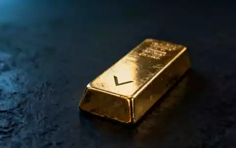 Ein einzelner, leicht angelaufener Goldbarren auf einer dunklen Oberfläche, der einen subtilen Abwärtstrend andeutet. - Foto: über boerse-global.de