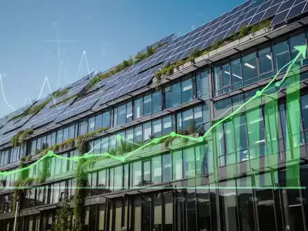 Eine moderne Bürogebäude-Fassade mit Solarpaneelen und grünen Elementen, die Energieeffizienz und Nachhaltigkeit symbolisiert. - Foto: über boerse-global.de