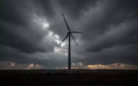 Eine einzelne Windkraftanlage vor einem stürmischen Himmel, die langfristige Energieprojekte symbolisiert. - Foto: über boerse-global.de