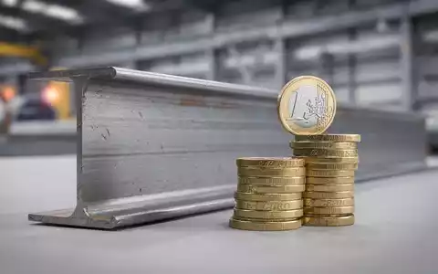 Ein Voestalpine Stahlträger mit einem Stapel Euromünzen im Vordergrund, die eine Dividendenerhöhung symbolisieren. - Foto: über boerse-global.de