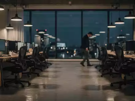 Ein leeres, modern eingerichtetes Büro mit Schreibtischen und Stühlen. Eine verschwommene Person geht im Hintergrund weg. - Foto: über boerse-global.de