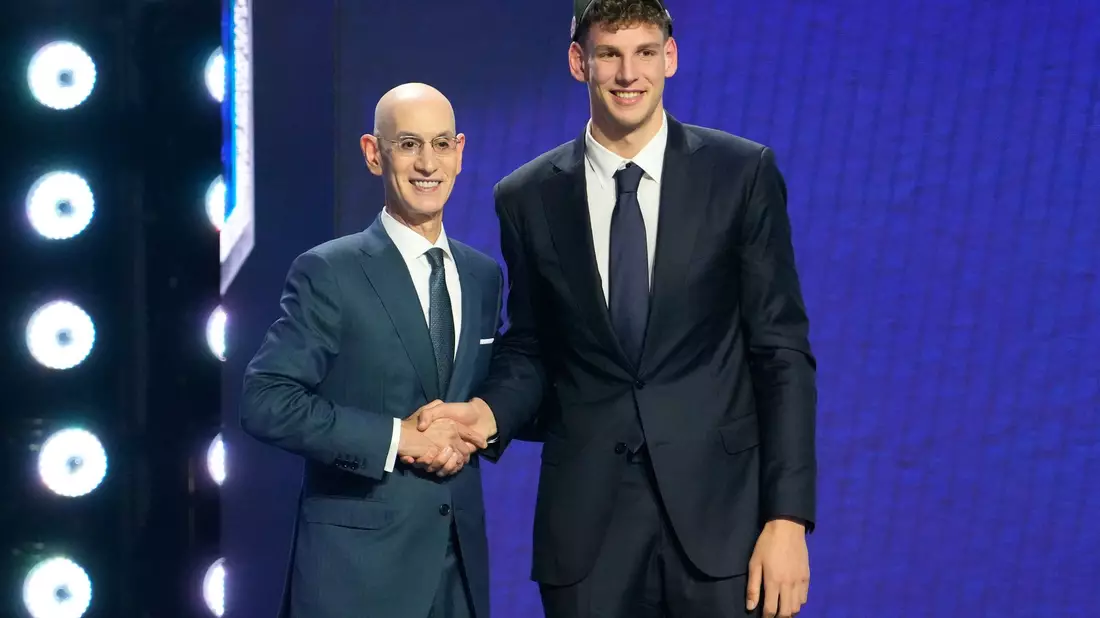 NBA-Commissionar Adam Silver (l) gratuliert Hannes Steinbach. - Bild: Yuki Iwamura/AP/dpa