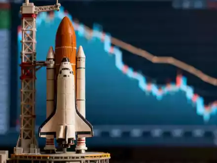 Eine Miniaturrakete startet im Vordergrund, unscharf. Im Hintergrund ein stilisierter Finanzchart mit abnehmendem Trend. - Foto: über boerse-global.de