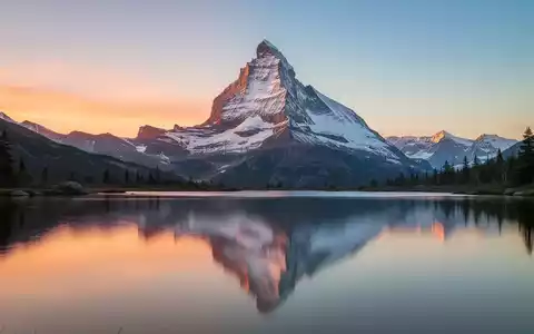 Ein majestätischer, silberner Berggipfel spiegelt sich bei Sonnenaufgang in einem ruhigen See wider. - Foto: über boerse-global.de