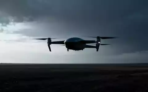 Eine moderne Drohne fliegt über eine weite Landschaft unter einem leicht bedrohlichen Himmel, die Silhouette betont ihre Technologie. - Foto: über boerse-global.de