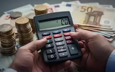 Eine Hand hält einen Taschenrechner, der eine negative Zahl anzeigt, mit verschwommenen Euro-Münzen und -Scheinen im Hintergrund. - Foto: über boerse-global.de